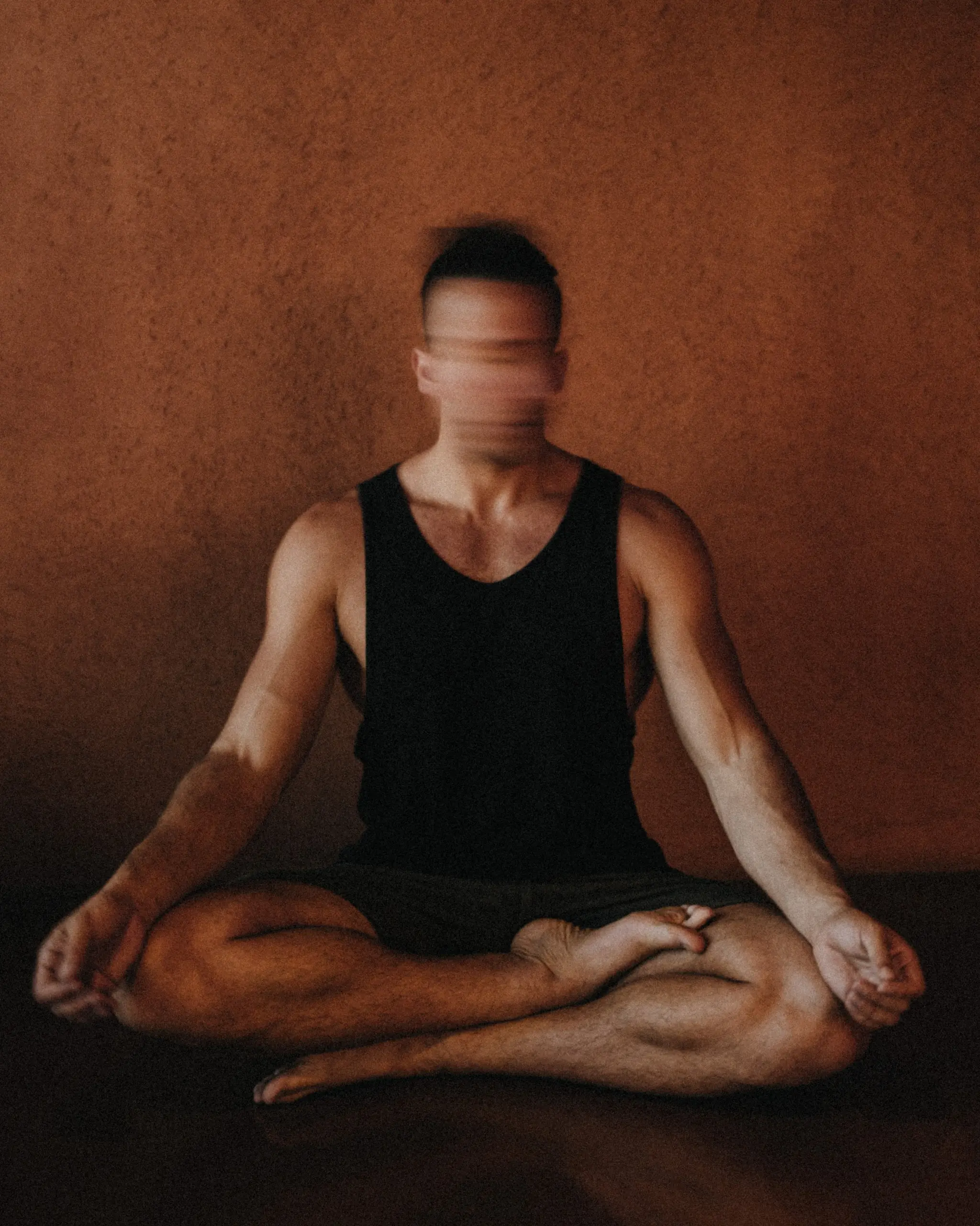 Jonah Kest crouching beside students resting in child's pose in a warm wooden shala in Bali